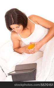 Young beautiful woman having breakfast in bed while working or relaxing with her computer