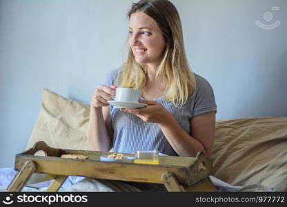 Young beautiful woman having breakfast on bed at home.