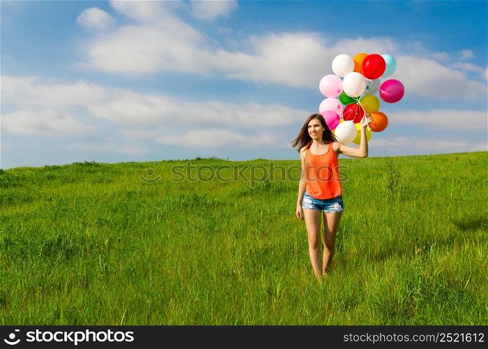 Young beautiful woman having fun with balloons on a green meadow