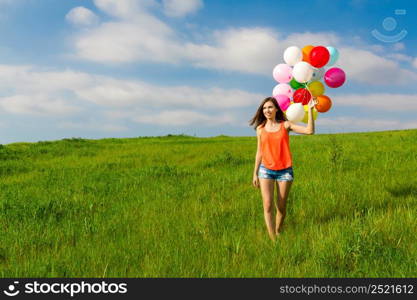 Young beautiful woman having fun with balloons on a green meadow