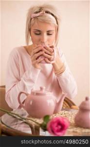 Young beautiful woman having tea-party in pink feminine style. She is very satisfacted. Valentine's day or international women's day celebration.