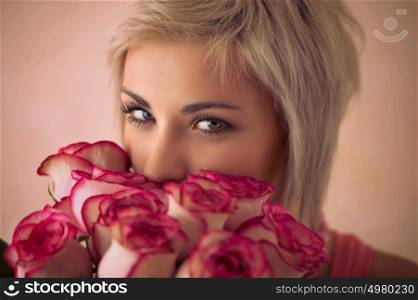 Young beautiful woman holding bouquet of pink roses. She is very satisfacted. Valentine's day or international women's day celebration.