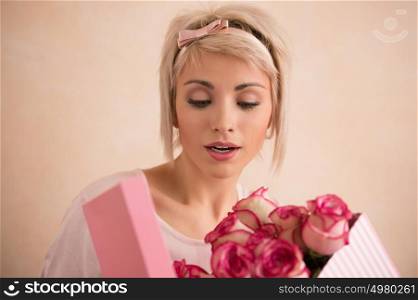 Young beautiful woman holding bow with bouquet of pink roses inside. She is very satisfacted. Valentine's day or international women's day celebration.