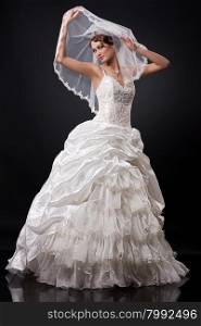 Young beautiful woman in a fashionable wedding dress on a black background