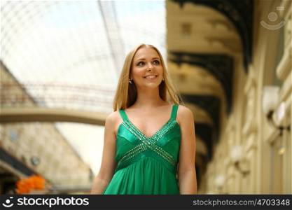 Young beautiful woman in a long green dress walking in the mall