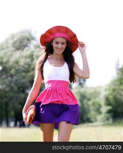 Young beautiful woman in a red hat in summer park