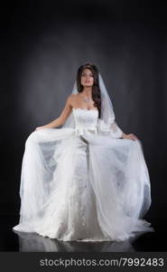 Young beautiful woman in a wedding dress on a studio background