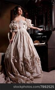 Young beautiful woman in a wedding dress standing near the old secretaire