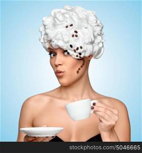 Young beautiful woman in a whipped cream with a curl made of roasted coffee beans on her head, drinking coffee and holding a coffee cup on blue background.