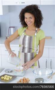 young beautiful woman in an apron making cake