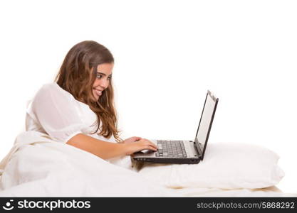 Young beautiful woman in bed, working or relaxing with her computer