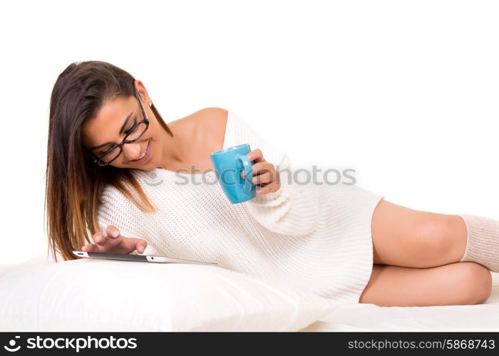 Young beautiful woman in bed, working or relaxing with her computer