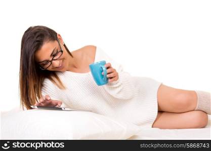 Young beautiful woman in bed, working or relaxing with her computer