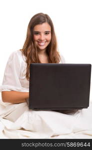 Young beautiful woman in bed, working or relaxing with her computer