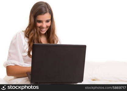 Young beautiful woman in bed, working or relaxing with her computer