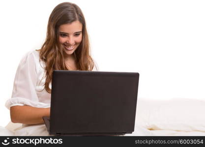 Young beautiful woman in bed, working or relaxing with her computer