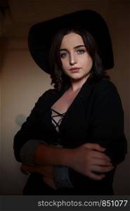 young beautiful woman in black jacket with black hat and black underwear posing in the sunset