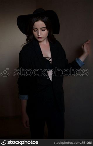 young beautiful woman in black jacket with black hat and black underwear posing in the sunset