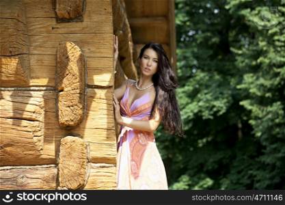 Young beautiful woman in bright dress near the wooden wall