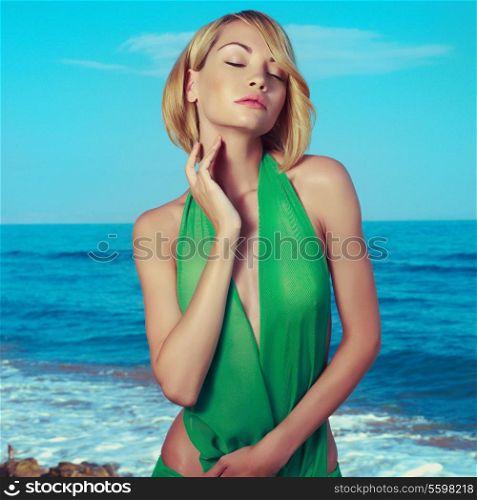 Young beautiful woman in green dress on the beach