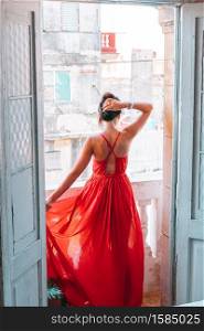 Young beautiful woman in red dress on old balcony in apartments in Havana at Cuba. Young attractive woman in red dress on old balcony in apartment in Havana