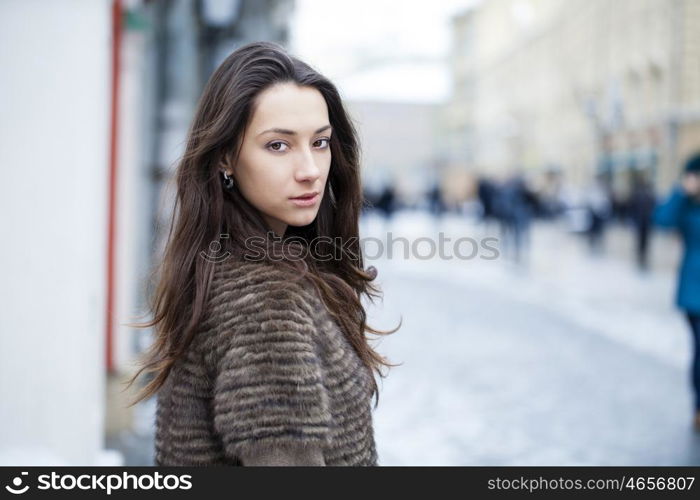 Young beautiful woman in stylish mink coat on a background of a winter street