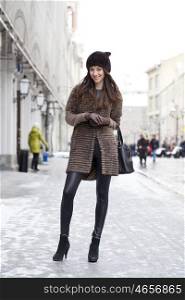 Young beautiful woman in stylish mink coat on a background of a winter street