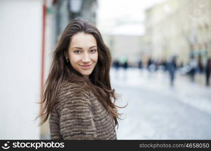 Young beautiful woman in stylish mink coat on a background of a winter street