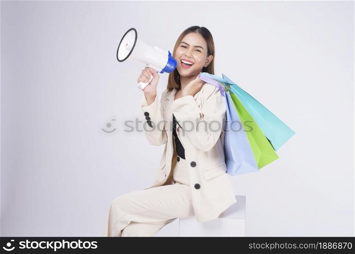 Young beautiful woman in suit holding colorful shopping bags over white background studio