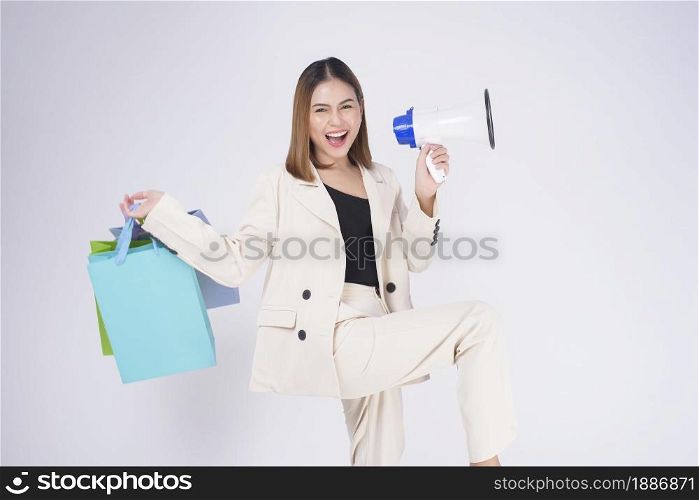 Young beautiful woman in suit holding colorful shopping bags over white background studio