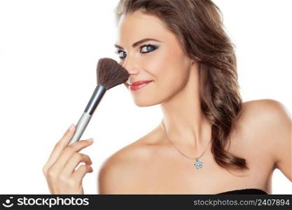 Young beautiful woman joking with a make-up brush, isolated on white