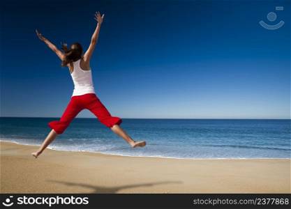 Young beautiful woman jumping in the beach