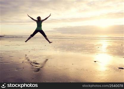 Young beautiful woman jumping in the beach
