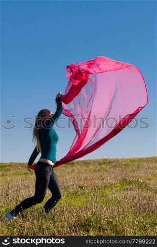 young beautiful woman jumping with tissue into the field against the sky