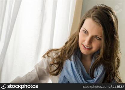 Young beautiful woman looking window behind curtain romantic portrait