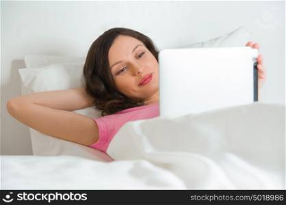 Young Beautiful Woman Lying On Bed And Holding Digital Tablet