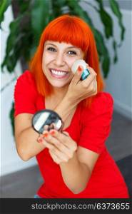 Young beautiful woman making make-up near mirror