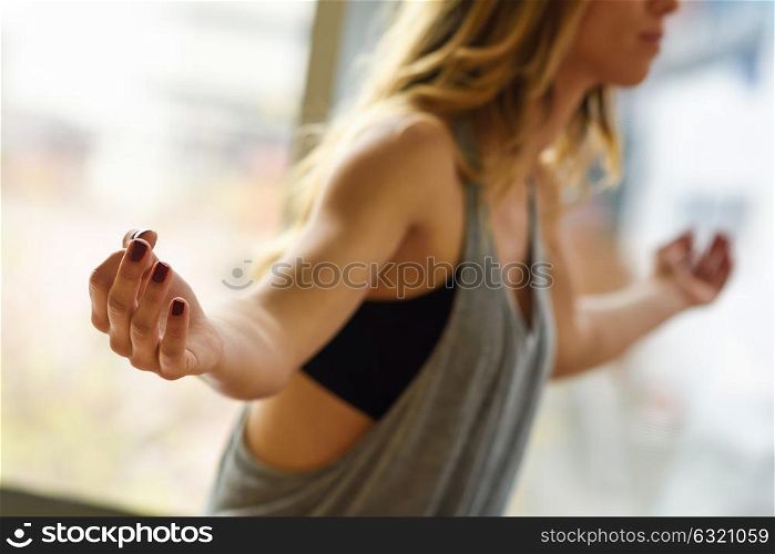 Young beautiful woman meditating in the lotus position in gym. Girl wearing sportswear clothes.