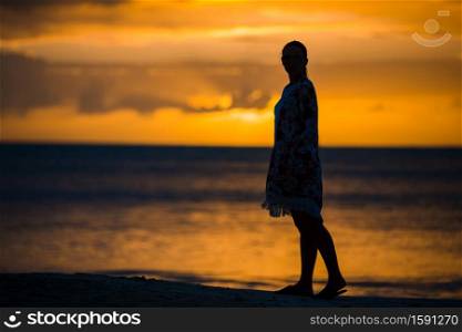 Young beautiful woman on the beach at sunset. Young fashion woman in green dress on the beach