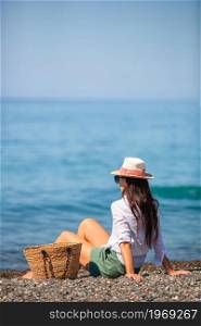 Young beautiful woman on the beach sunbathers. Concept of health beach vacation - sun creams, straw hat, sunglasses . Young woman in hat on the beach vacation