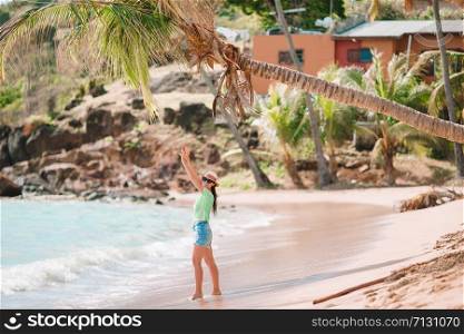 Young beautiful woman on tropical seashore. Happy girl relaxes at white sand tropical beach. Young beautiful woman having fun on tropical seashore.