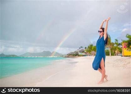 Young beautiful woman on tropical seashore. Happy girl relaxing at white sand tropical beach background beautiful rainbow. Young beautiful woman on tropical seashore. Happy girl relaxing at white sand tropical beach