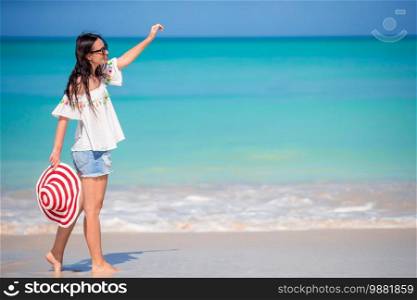 Young beautiful woman on white sand tropical beach. Caucasian girl with hat background the sea. Young fashion woman in hat on the beach