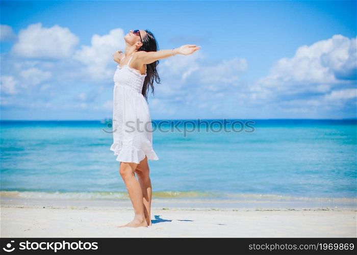 Young beautiful woman on white sand tropical beach. Young woman in white on the beach