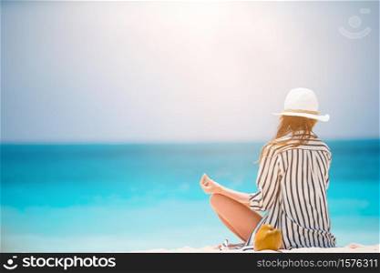 Young beautiful woman on yoga on white sand tropical beach.. Young fashion woman in green dress on the beach