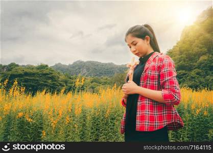 Young beautiful woman praying on nature background. Hope and faith concept.