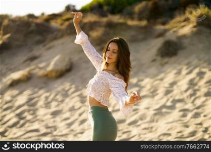 Young beautiful woman raising her arms standing on the sand of the beach. Young woman raising her arms standing on the sand of the beach