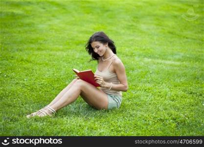 Young beautiful woman reading a book outdoor