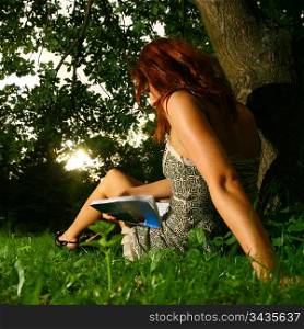 young beautiful woman reading book in forest