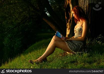 young beautiful woman reading book in forest